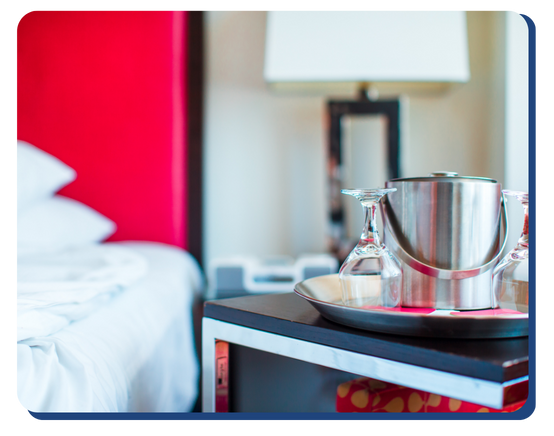 Close-up of a freshly cleaned hotel room featuring an ice bucket and glasses on a nightstand, showcasing attention to guest comfort and hygiene standards.