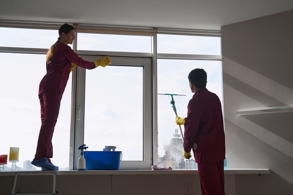 janitorial staff using microfiber cloth and squeegie