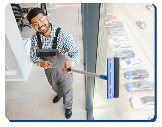 Smiling professional cleaner washing retail windows with a squeegee, highlighting expert retail cleaning for high-traffic storefronts and visibility.