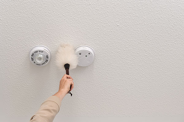 Hand performing high dusting on ceiling smoke detectors for Toronto high dusting services. Hand performing high dusting on ceiling smoke detectors for Toronto high dusting services.