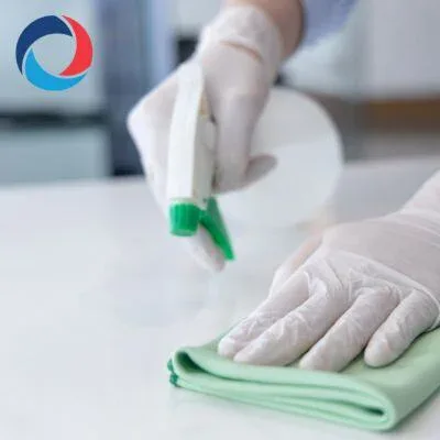 A person wearing white gloves cleans a surface with a green cloth and sprays cleaner, with the impact commercial cleaning services blue and red logo visible in the upper left corner.