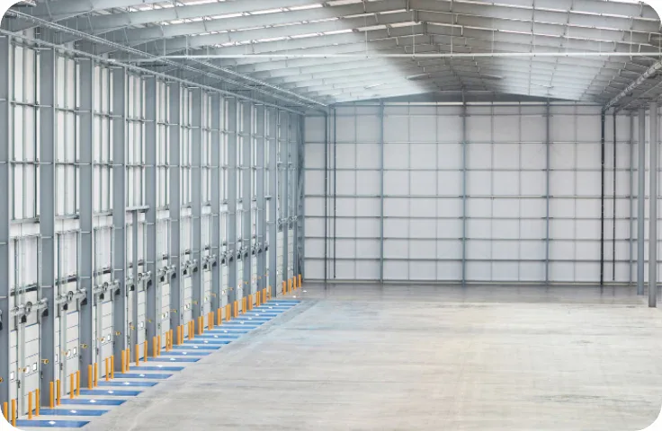 Spacious warehouse interior with polished concrete floors, high ceiling, and large windows. Multiple closed loading dock doors line the left wall, and natural light fills the space—ideal for commercial cleaning Canada or Impact Commercial Cleaning Services.